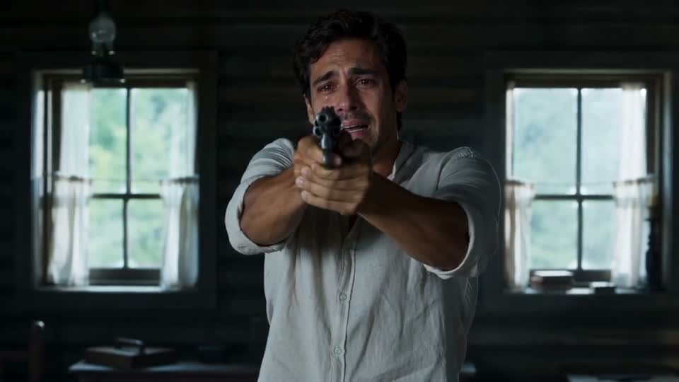 The fictional male survivor in our Zombie Love Story sample aims a gun in the dark cabin
